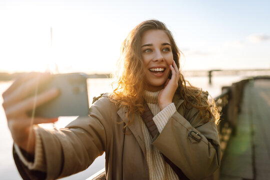 Happy woman with a mobile phone, takes a selfie, communicates with friends, blogs outdoor. Lifestyle, travel, tourism, nature, active life.