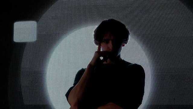 Male model against digital wall. Man silhouette posing on runaway catwalk fashion show in front of digital screen wall background in club.
