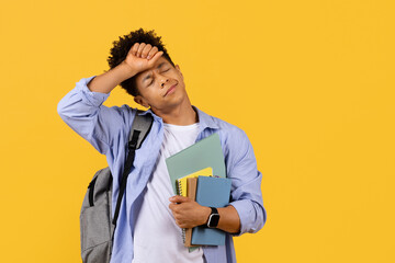 Stressed black student guy with books, overwhelmed by study load