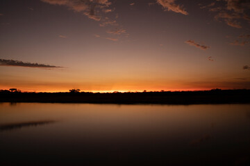 Long exposure shot of the river and coast at nightfall. Beautiful sunset sky reflection in the water surface.	
