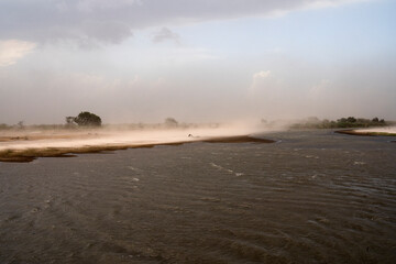 Panorama view of the river and beach under a wind storm that raises the sand.  