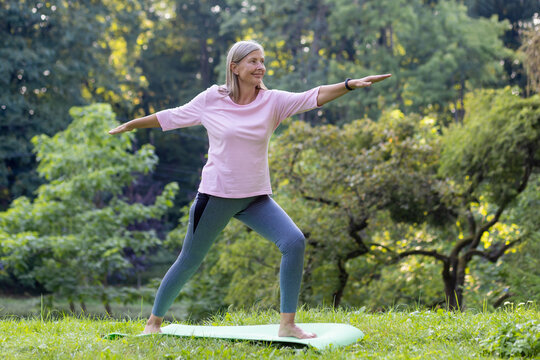 An elderly woman enjoys a peaceful yoga session in a green park, demonstrating health and vitality in her golden years.