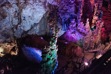 Natural cave with stalactites and stalagmites with lighting.