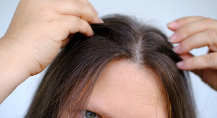 Fototapeta premium close up middle-aged female face, woman 45-50 years old looks gray hair, carefully examines hair, Aging with grace and confidence, age-related changes, Self-esteem and self-image at any age