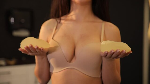 Woman planning to have a breast implant. Silicone implants on hand and natural breast.