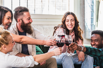 joyful friends toasting with red wine in a bright living room