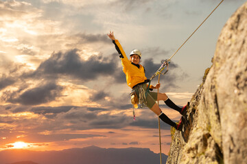 woman climbing in the mountain at sunset with lus rays, security, confidence business woman, rope...