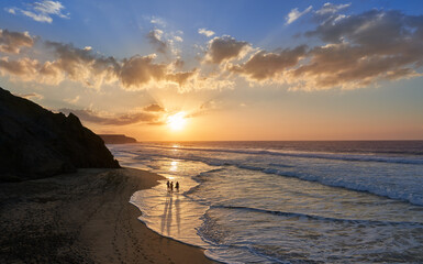 Drei Menschen stehen im Sonnenuntergang in einer sandigen Bucht am Strand - La Pared, Fuerteventura