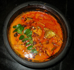 mackerel fish curry in a black bowl with curry leaf on top