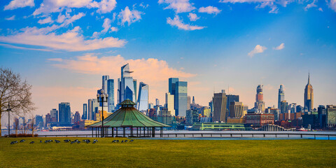 Hoboken Pier C Panoramic Viewpoint Park at Sunrise with Brant Geese grazing on the green lawn and New York City Lower Manhattan Skyline and skyscrapers in the background in New Jersey, USA - obrazy, fototapety, plakaty