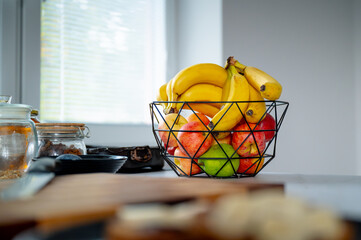 Pleasant sunlight accentuates a banana in a glass bowl on the kitchen counter - 747564707