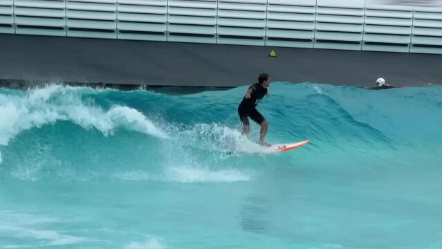 Beginner surfer rides the artificial wave and trains in the surfing pool
