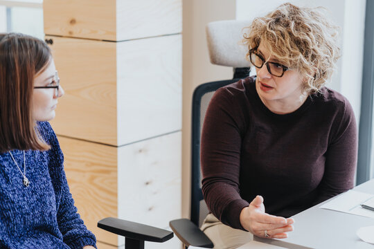 Professional women engaged in serious discussion at office table.