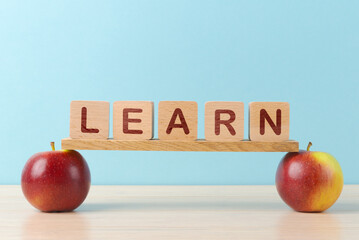 Wooden Blocks Spelling ‘LEARN’ Balanced on Apples