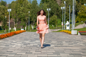 Full body portrait of a young beautiful brunette girl in a pink summer dress