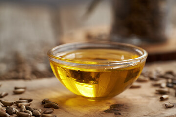 Milk thistle oil in a glass bowl with Carduus marianus seeds