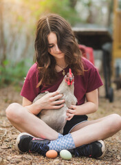 Young girl holding chicken in lap