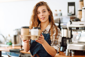 Portrait of young barista woman serving hot coffee. Takeaway food concept
