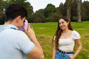 Two young teenage latino friends who are taking pictures with an instant camera