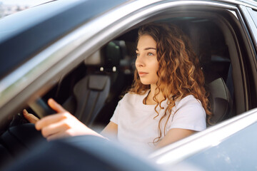 Female driver. Portrait of young woman is driving a car and smiling. Automobile travel.