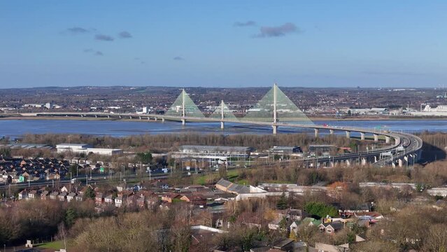 Drone cityscape view with the Mersey Gateway Bridge in the background under blue sky in Runcorn