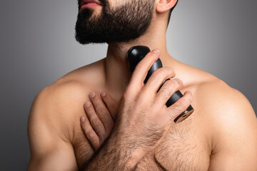 Cropped of young muscular man trimming his beard