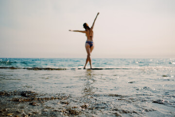 A woman in a swimsuit expresses joy with open arms against the backdrop of the glistening...