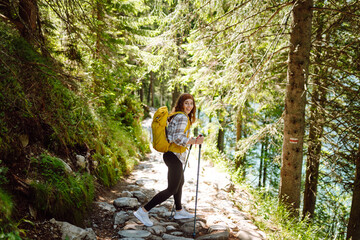 Young woman with backpacks and walking sticks hiking in nature. Adventure, travel, sport, active...