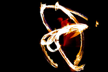 Blurred flames moved by fire juggler with dark background. Long shutter speed photo.
