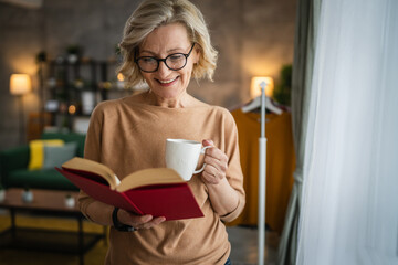 One woman mature caucasian female read book at home wear eyeglasses