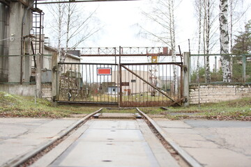 Railway tracks run into the metal gate of the industrial zone of the plant