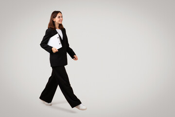 Confident professional woman strides forward with a clipboard in hand