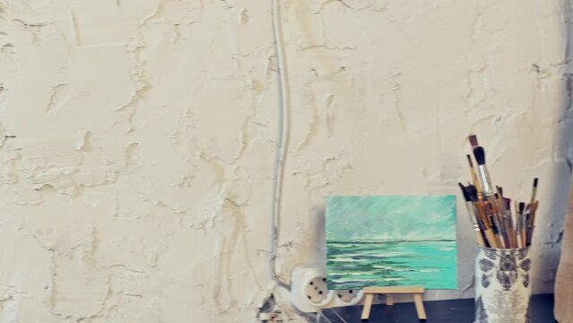Camera panoramic move from the still life on the table to the painting. Girl painting a jug with oil paints. Artist’s workshop.  