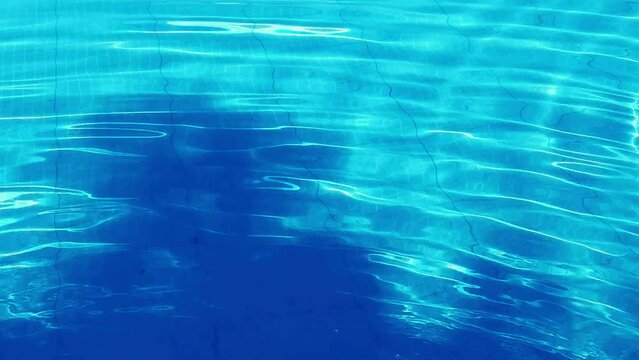 blue water in swimming pool in Slow motion with transparent shadow overlay effect. Abstract blue water wave surface texture with reflection sunlight