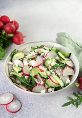 Vegetarian salad of radishes, cottage cheese, sour cream and arugula on a white background. 