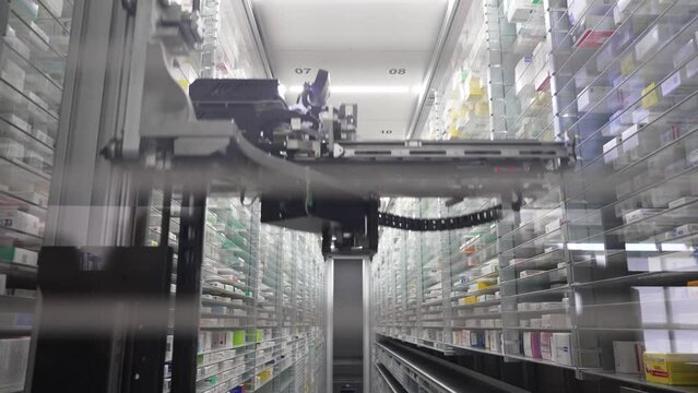 A pharmacy storage room and a robot hand are arranging and store out drugs in a pharmacy.