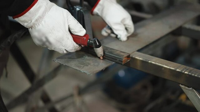 Process of cutting steel plate with gas welding torch in workshop, oxy fuel torch heating measured metal surface and then cutting with flame sparks. Metal industry worker in protective gloves cutting