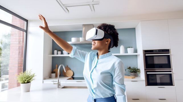 african american woman in white augmented virtual reality glasses gesticulates with her hands while controlling a virtual screen while standing in a modern home kitchen.