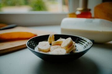 Sunlit breakfast scene: Banana paired with yogurt and crunchy oats - 747592946