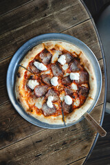 Appetizing Italian pizza with cheese and meat on a metal stand.