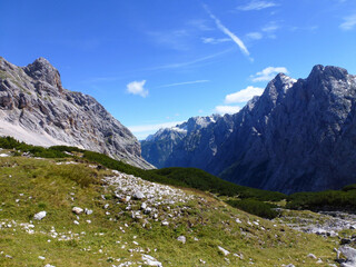 A beautiful mountain landscape of rocky mountain slopes on which stones are scattered and grass...