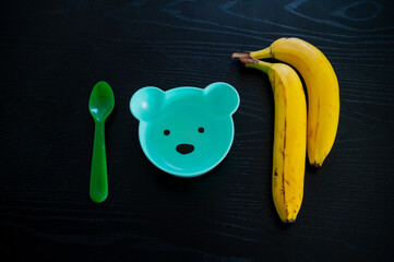 Banana and baby bowl in the shape of a bear. Feeding a toddler with fruit - 747594919