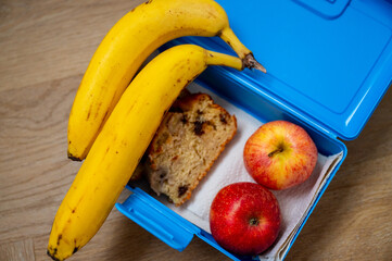 Morning essentials neatly packed for a day at school or the office: Banana, apples, and banana bread for a quick snack. - 747595991