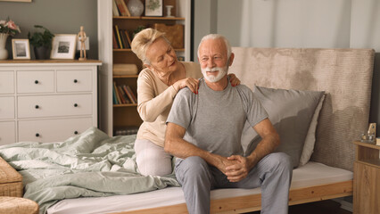 Elderly woman massaging her husband in bed