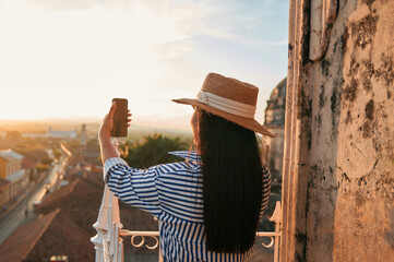 Tourist woman holding a smartphone during sunset from view point