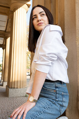 The girl at the column on the street. A girl in a white shirt with a thoughtful look.
