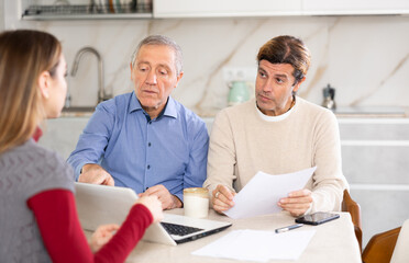 Obraz premium Elderly man and adult man discussing deal with seller in kitchen