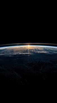 The sun gradually rises over the Earths horizon in space, casting a warm glow in the darkness.