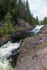 Beautiful landscape with waterfall in northern forest on summer. Powerful stream of water among stone rocks and green foliage. Kivach waterfall at Suna river in Karelia, Russia.	
