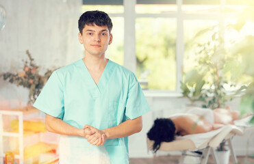 Obraz premium Young guy masseur in uniform posing in massage salon